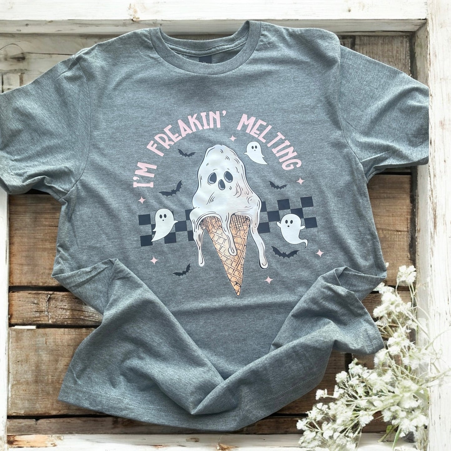 Gray t-shirt with a ghost in an ice cream cone graphic and text on a wooden surface.