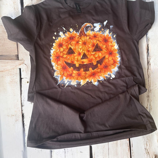 Black t-shirt with a pumpkin design made of flowers on a wooden surface