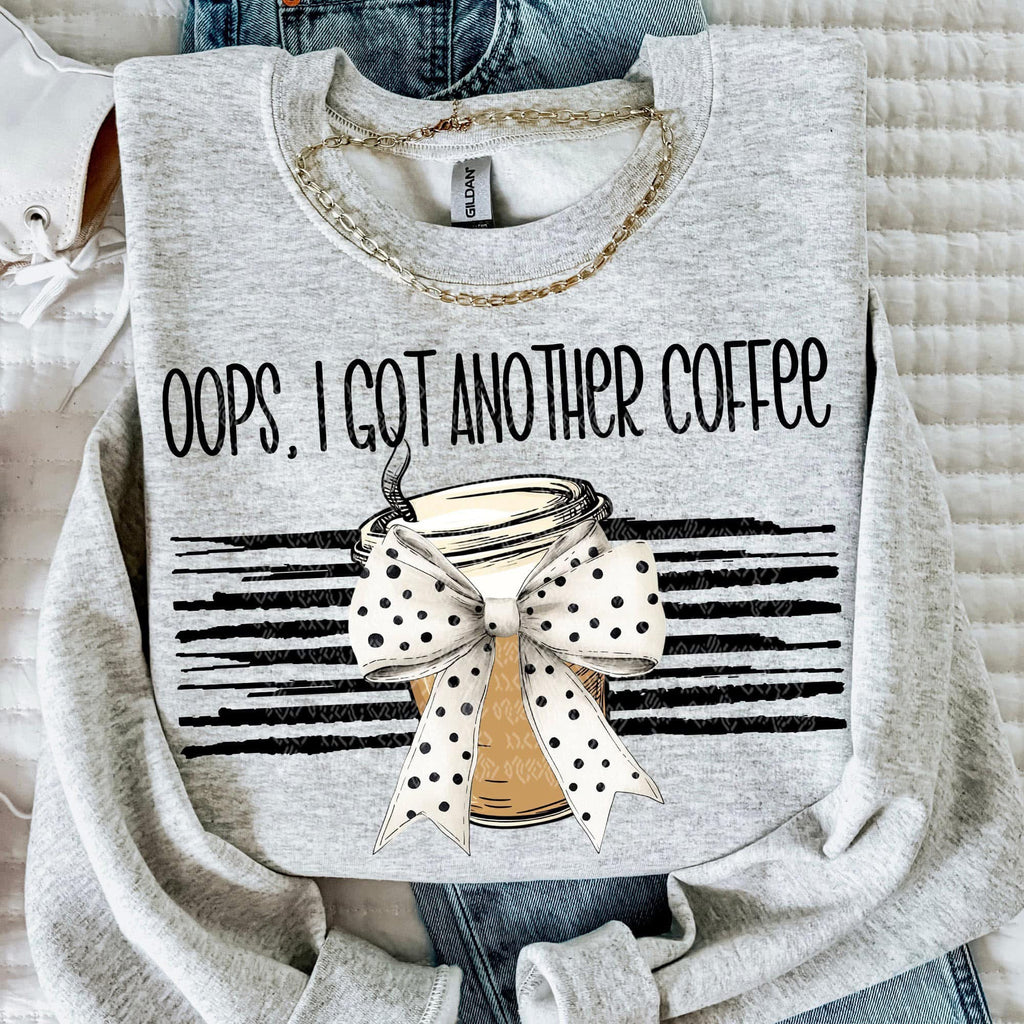 Gray sweatshirt with a coffee cup graphic and text 'Oops, I got another coffee' on a textured surface.