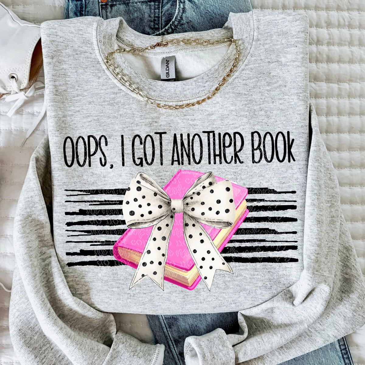 Gray sweatshirt with 'Oops, I got another book' text and a graphic of books and a bow.