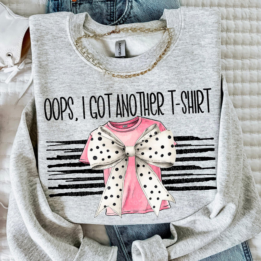 Gray t-shirt with graphic design and text 'Oops, I got another t-shirt' on a textured surface.