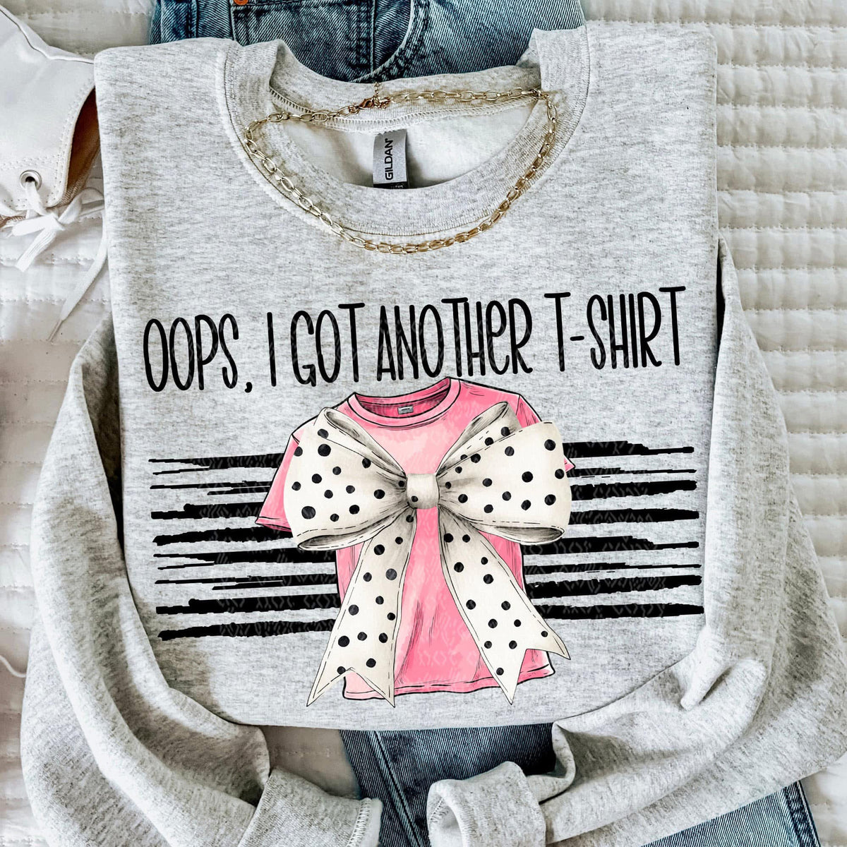 Gray t-shirt with graphic design and text 'Oops, I got another t-shirt' on a textured surface.