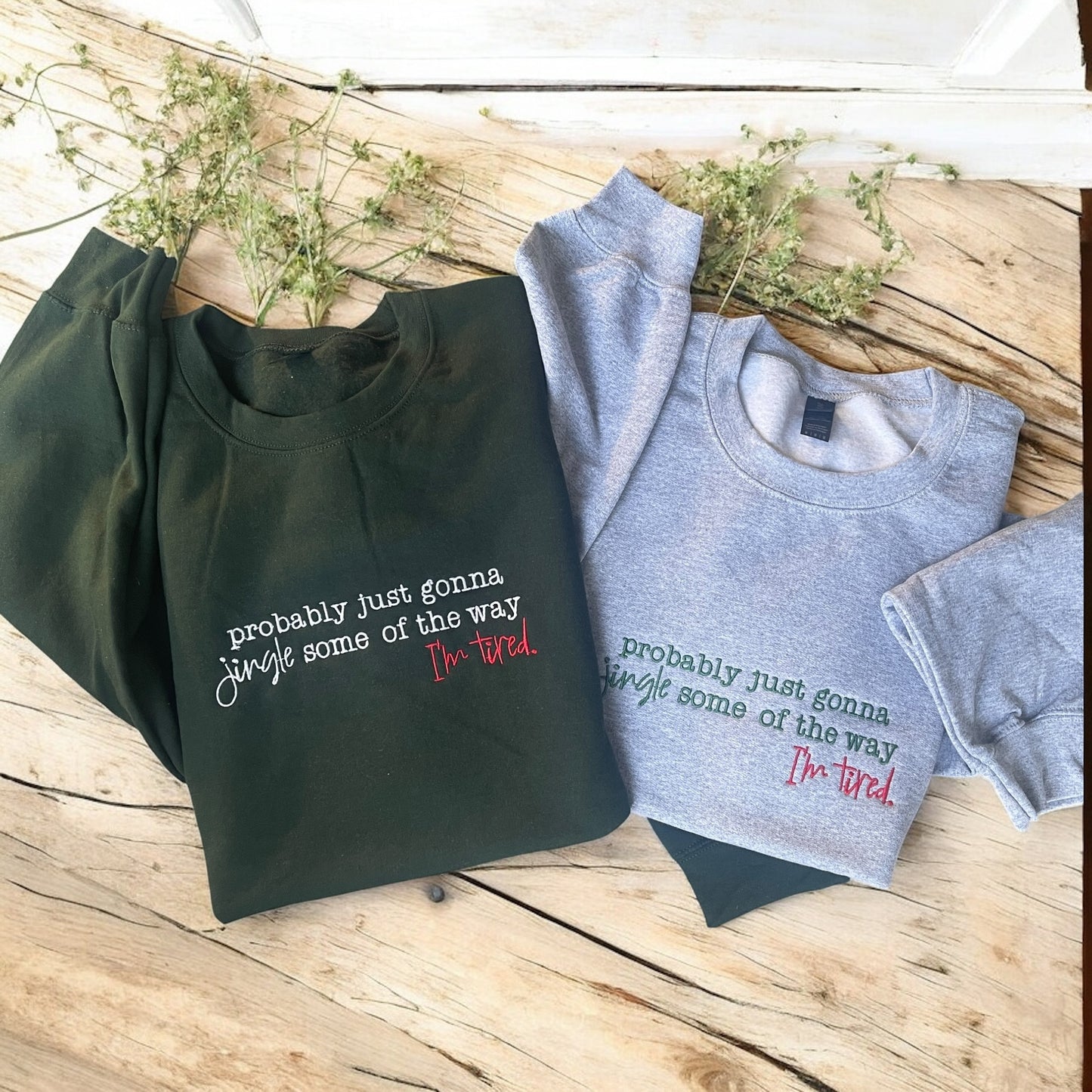 Black and gray sweatshirts with humorous text on a wooden surface.