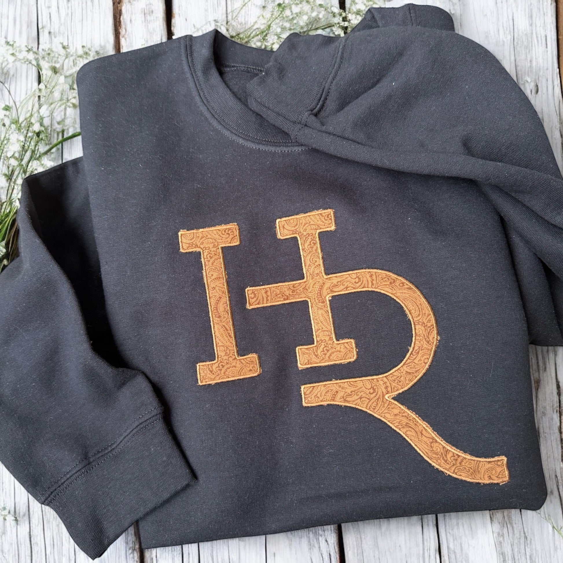 Dark gray sweatshirt with 'HR' logo on a wooden surface