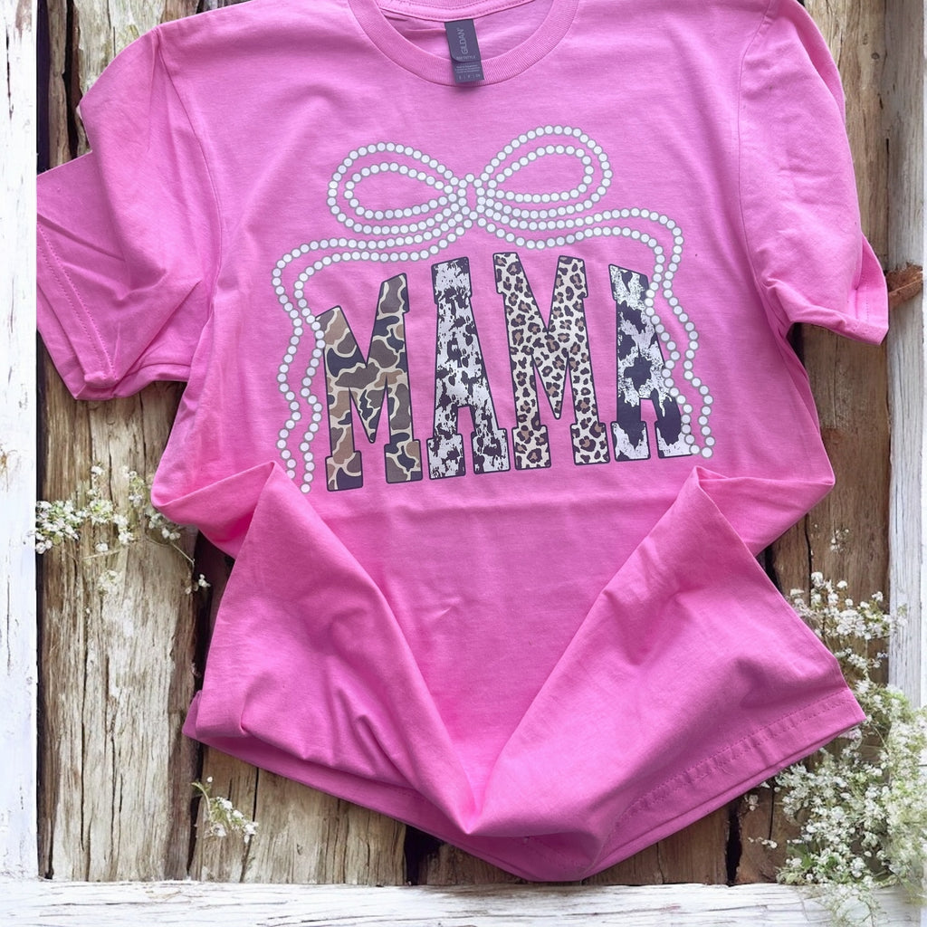 Pink t-shirt with leopard print 'MAMA' design on a wooden surface.
