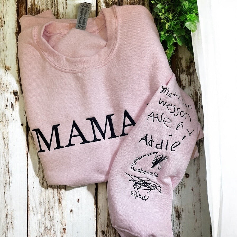 Pink sweatshirt with 'MAMA' and personalized names on a wooden surface