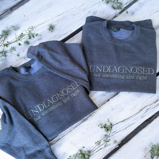 Two folded blue sweatshirts with text on a wooden surface