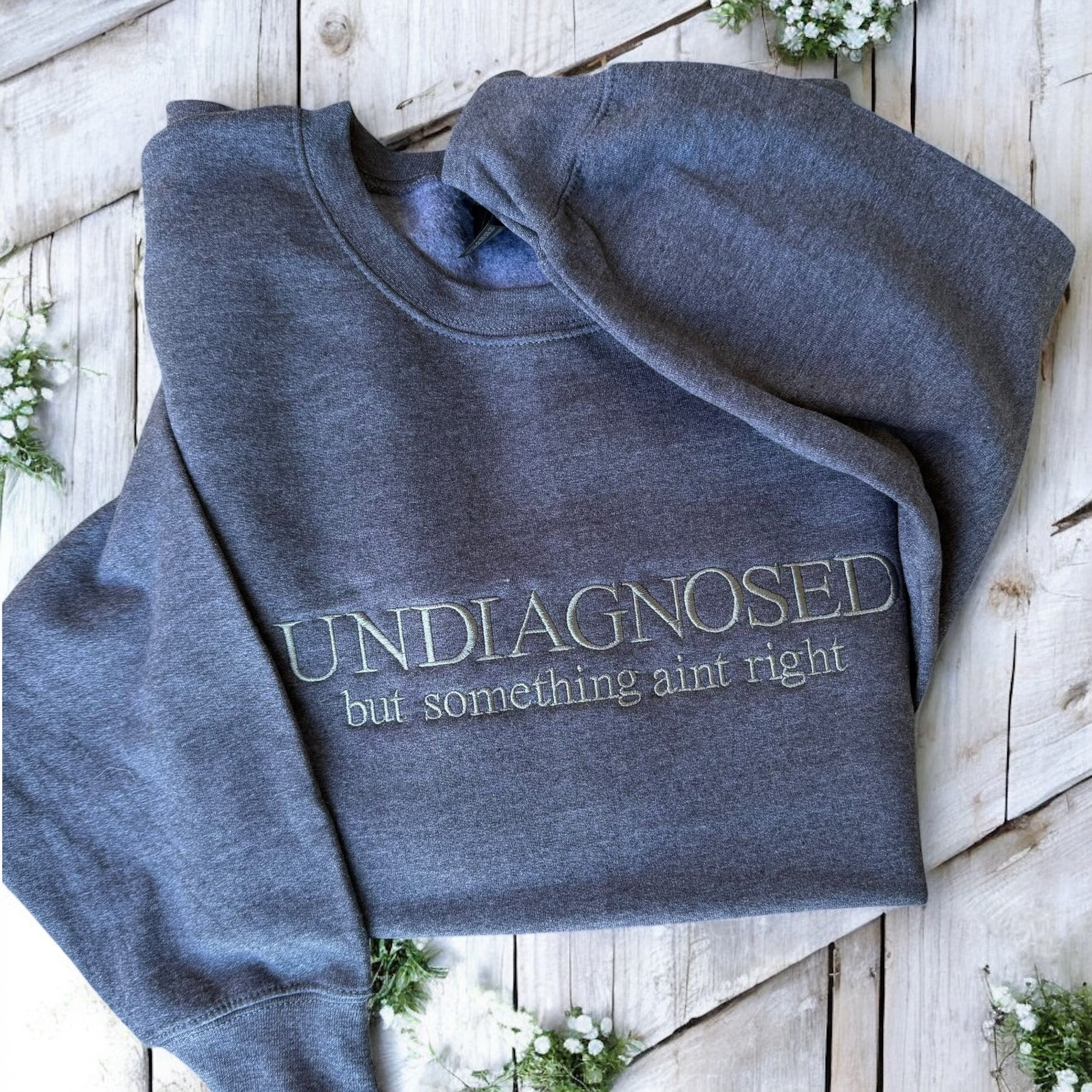 Folded blue sweatshirt with text on a wooden surface